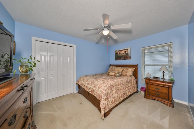 carpeted bedroom featuring ceiling fan, a textured ceiling, and a closet