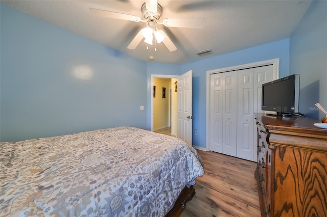 bedroom featuring ceiling fan, a closet, a textured ceiling, and light wood-type flooring