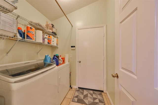 washroom with light tile patterned floors, a textured ceiling, and washing machine and clothes dryer