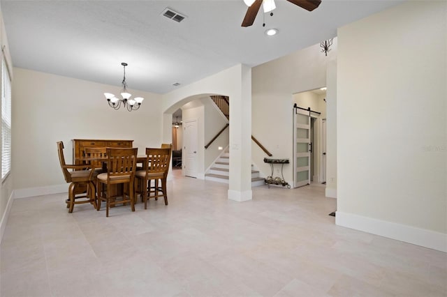 dining room featuring a barn door and ceiling fan with notable chandelier