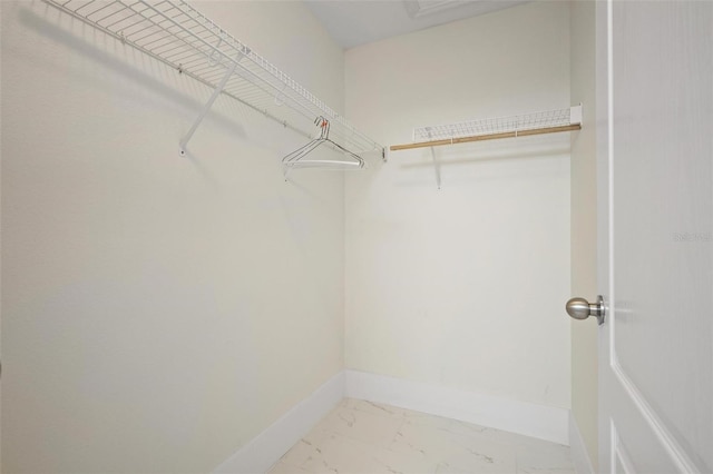 walk in closet featuring marble finish floor