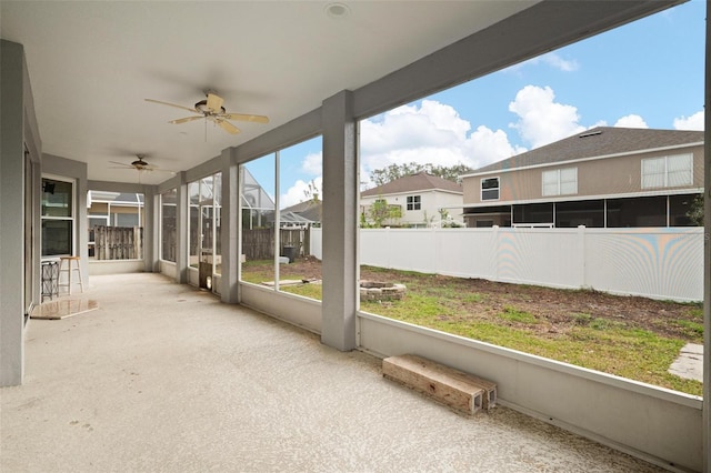 unfurnished sunroom with a residential view, a healthy amount of sunlight, and ceiling fan