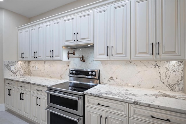 kitchen featuring tasteful backsplash, light stone countertops, and range with two ovens