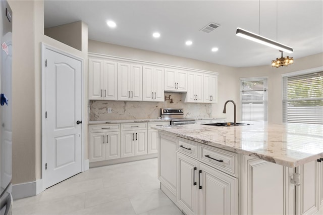 kitchen with visible vents, a sink, decorative backsplash, stainless steel range with electric stovetop, and white cabinets