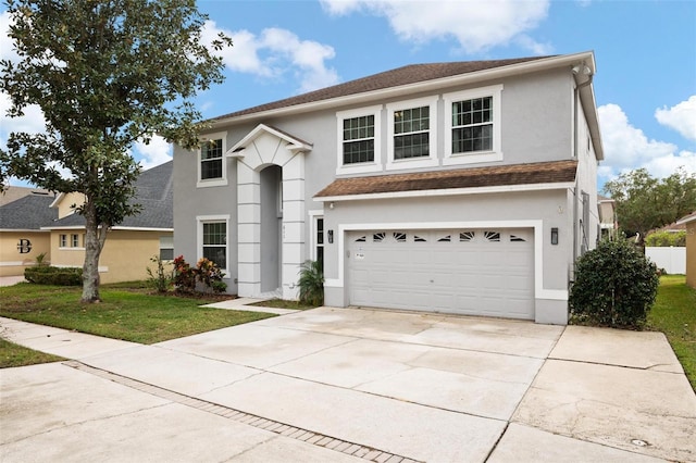 traditional-style home featuring stucco siding, an attached garage, driveway, and a front yard