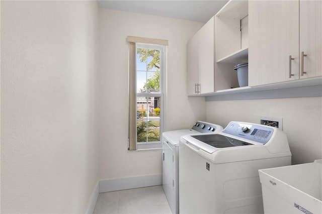 clothes washing area with independent washer and dryer, a sink, cabinet space, tile patterned flooring, and baseboards