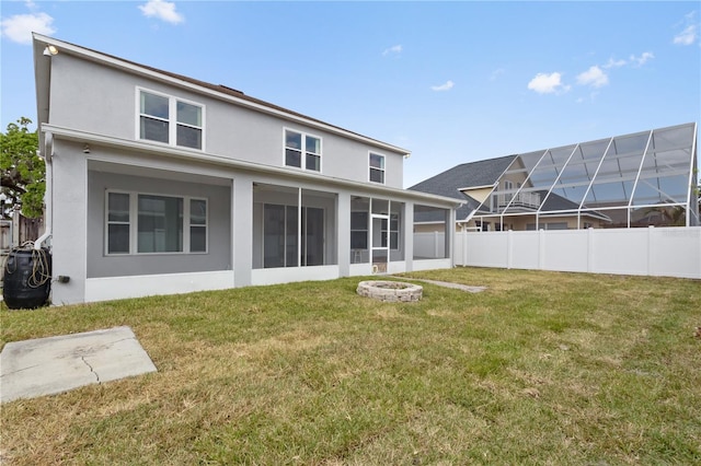 back of property featuring stucco siding, a sunroom, a lawn, and fence