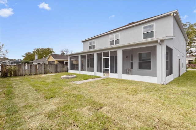 rear view of house with fence, an outdoor fire pit, a sunroom, stucco siding, and a lawn