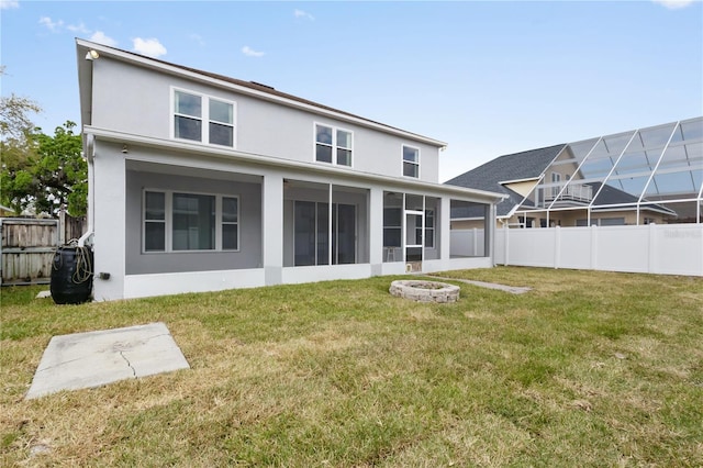 back of house with stucco siding, a sunroom, a yard, and fence