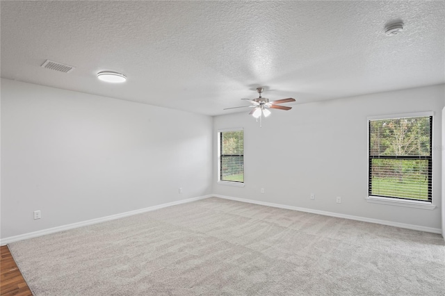 carpeted empty room featuring ceiling fan and a textured ceiling