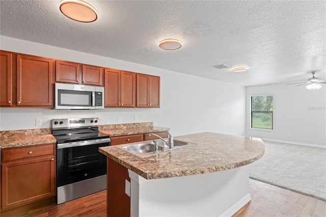 kitchen featuring sink, dark wood-type flooring, a center island with sink, and appliances with stainless steel finishes