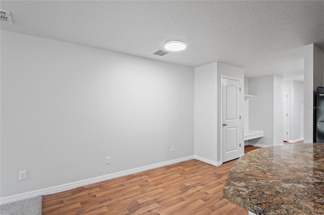 interior space with black refrigerator, hardwood / wood-style floors, and a textured ceiling