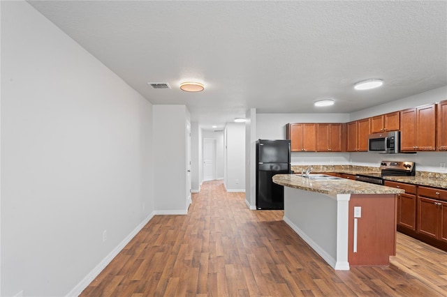 kitchen featuring sink, wood-type flooring, stainless steel appliances, and a kitchen island with sink