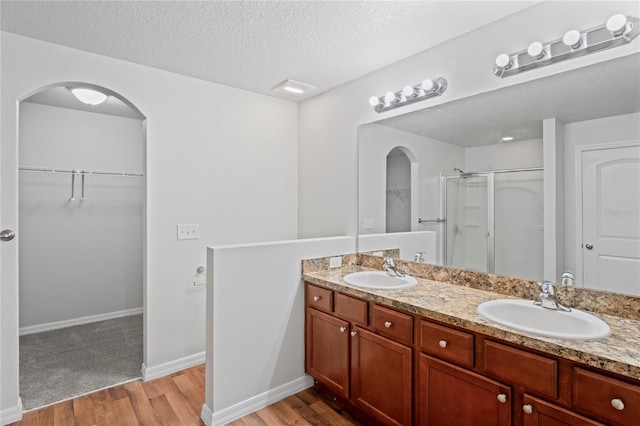 bathroom featuring a shower with door, vanity, a textured ceiling, and hardwood / wood-style flooring