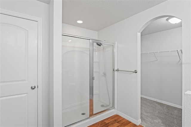 bathroom with wood-type flooring, a textured ceiling, and a shower with shower door