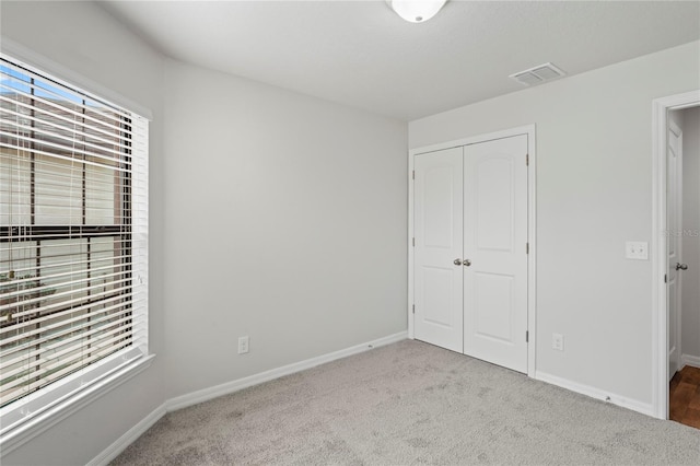 unfurnished bedroom with light carpet and a closet