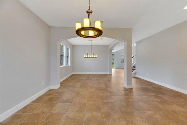 spare room with a chandelier and light tile patterned flooring