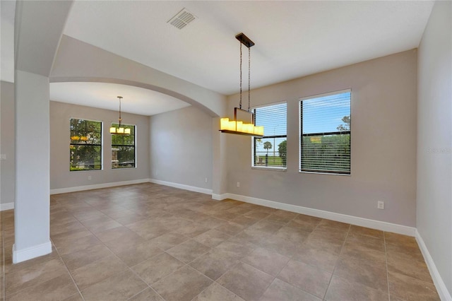 tiled spare room with a healthy amount of sunlight and a notable chandelier