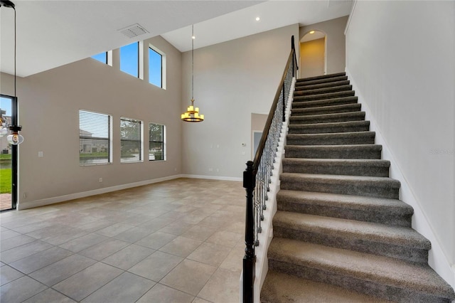 staircase with tile patterned flooring and a high ceiling