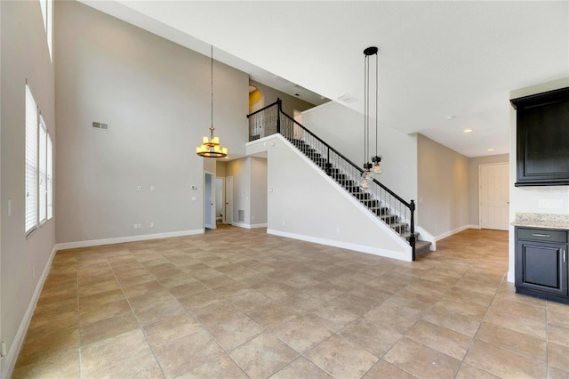 unfurnished living room with a towering ceiling and an inviting chandelier