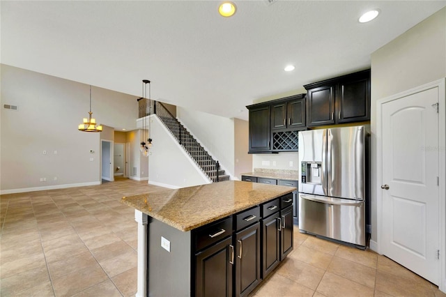 kitchen with a center island, light stone counters, stainless steel fridge, pendant lighting, and light tile patterned floors