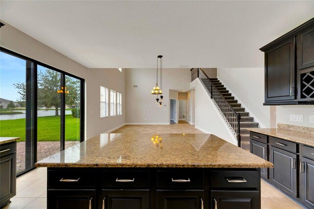 kitchen featuring a kitchen island, light stone countertops, and hanging light fixtures