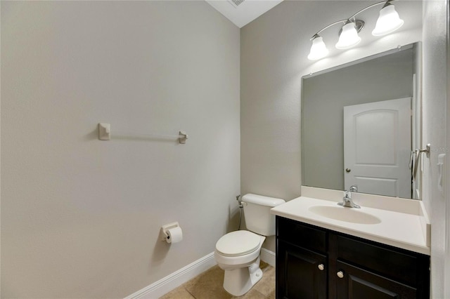 bathroom with toilet, vanity, and tile patterned floors