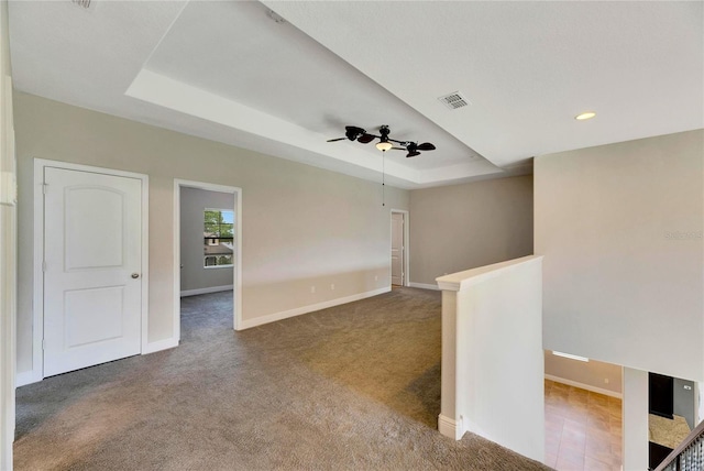 unfurnished room with carpet flooring, a raised ceiling, and ceiling fan