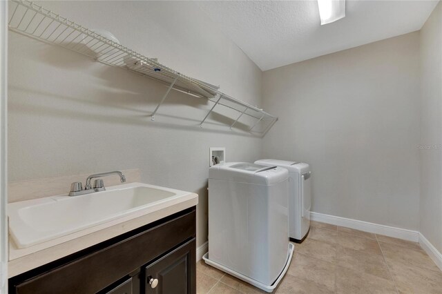 washroom featuring sink, cabinets, a textured ceiling, light tile patterned floors, and washer and dryer