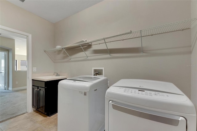 washroom featuring washer and clothes dryer, light tile patterned flooring, cabinets, and sink