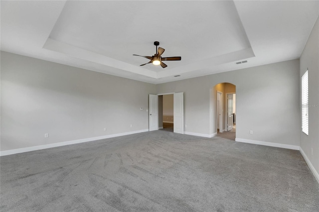 carpeted spare room with a tray ceiling and ceiling fan