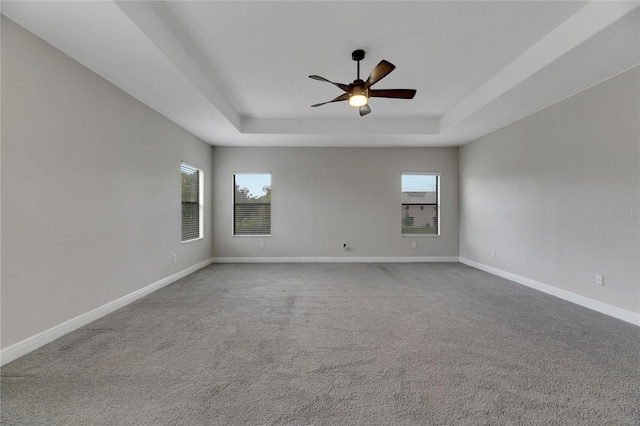 spare room featuring carpet floors, a raised ceiling, and ceiling fan