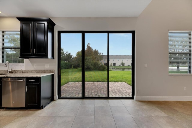 kitchen with a wealth of natural light, sink, light tile patterned floors, and stainless steel dishwasher