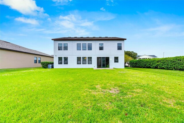 back of house with a yard and central AC