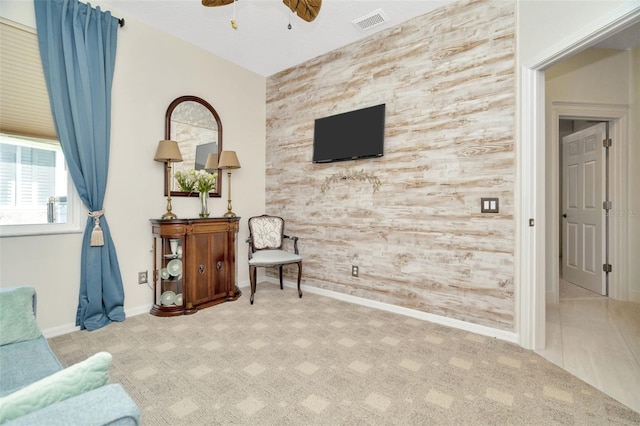 living area featuring light carpet and ceiling fan