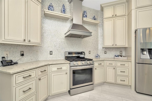 kitchen featuring appliances with stainless steel finishes, backsplash, light stone counters, wall chimney exhaust hood, and cream cabinetry