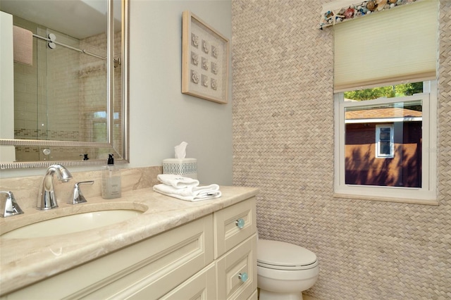 bathroom with tiled shower, vanity, and toilet