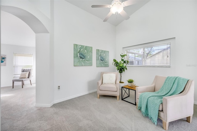 sitting room with a towering ceiling, light carpet, and ceiling fan