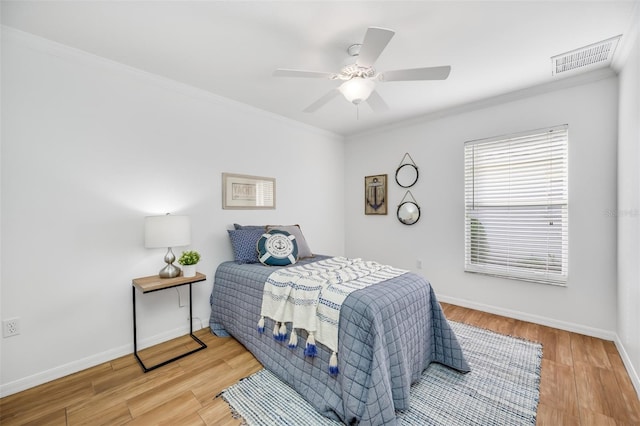 bedroom featuring hardwood / wood-style flooring, ornamental molding, and ceiling fan