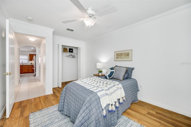 bedroom with ceiling fan, ornamental molding, hardwood / wood-style floors, and a closet