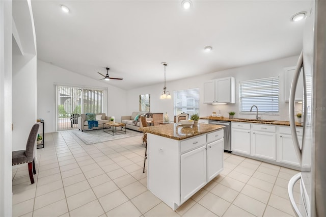 kitchen with sink, white cabinetry, dark stone countertops, stainless steel appliances, and a kitchen island