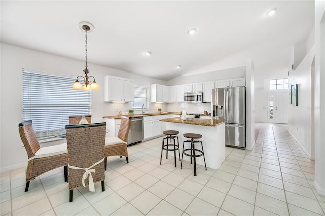 kitchen featuring appliances with stainless steel finishes, white cabinets, hanging light fixtures, a center island, and light tile patterned floors