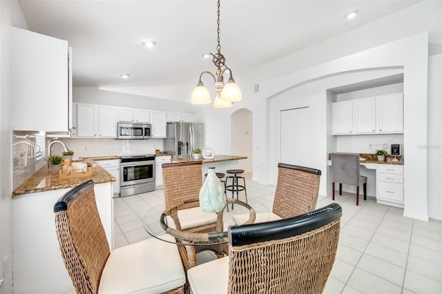 tiled dining space with sink, built in desk, and a notable chandelier