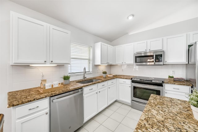 kitchen featuring sink, dark stone countertops, white cabinets, decorative backsplash, and stainless steel appliances