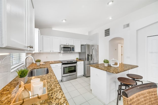 kitchen featuring stainless steel appliances, white cabinetry, sink, and dark stone counters