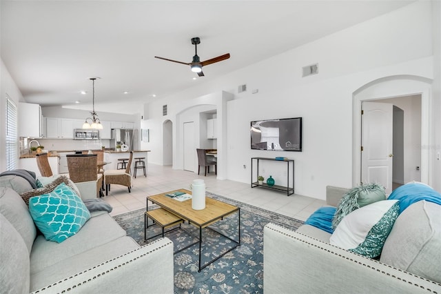 living room with lofted ceiling, ceiling fan with notable chandelier, and light tile patterned floors