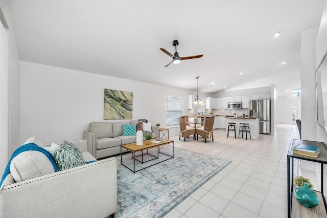 living room with ceiling fan, vaulted ceiling, and light tile patterned floors