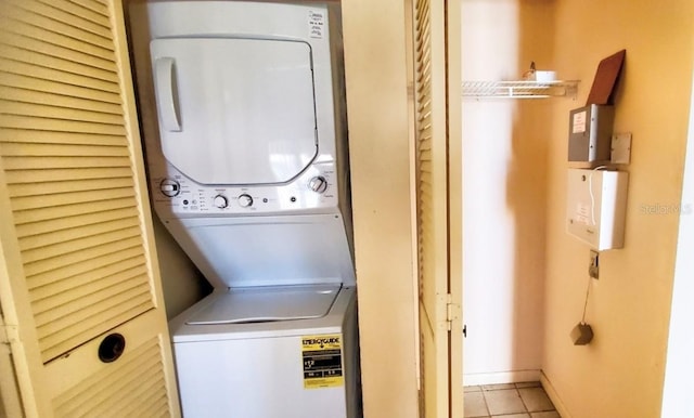 laundry area featuring stacked washer and clothes dryer and light tile patterned flooring