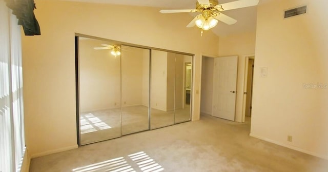 unfurnished bedroom with light colored carpet, high vaulted ceiling, a closet, and ceiling fan