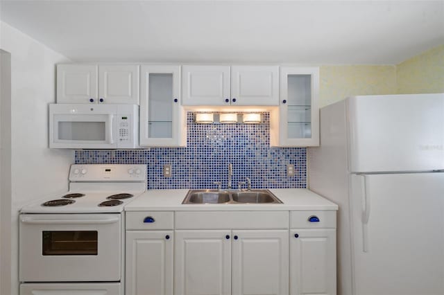 kitchen with white appliances, backsplash, white cabinetry, and sink